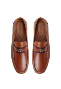 Mocasines de cuero marrón con una correa que presenta un acento de hardware en tono dorado, textura lisa y un diseño de punta redondeada.
