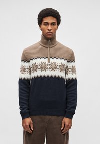 Camisola de malha castanha e azul-marinho com gola alta, apresentando um padrão geométrico em branco e castanho. Textura canelada na gola e nos punhos.