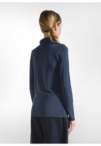 Polo lung cu mânecă lungă de culoare albastru închis, cu guler căptușit, realizat dintr-un material moale, având un design ajustat și o textură netedă, cu un tiv posterior mai lung.