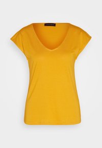 Chemise jaune à manches courtes avec un col en V et une étiquette noire portant la mention "Anna Field" à l’intérieur du col, présentée sur un fond uni.