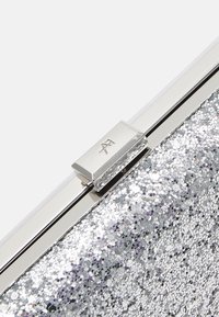 Silberne Glitzer-Clutch mit einem metallischen Verschluss, ausgestattet mit einer strukturierten Oberfläche aus hexagonalen Pailletten und in rechteckiger Form.