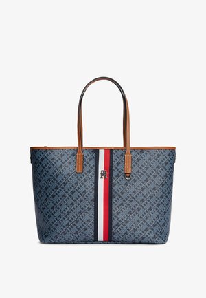 Grote blauwe tas met patroon en bruine leren handvatten en afwerking, met een verticale streep in het midden in marineblauw, wit en rood met een klein logo.