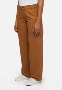 Cargo pants in warm brown fabric, featuring a side pocket and a relaxed, wide leg design. Paired with light-colored sneakers.