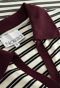 Polo shirt cu guler burgundy cu dungi; prezintă dungi negre și crem; material moale; include o etichetă cusută cu marca "Noella".