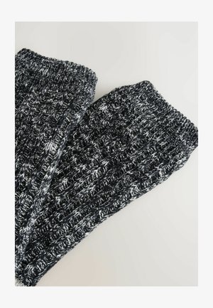Dobrze zrobione ocieplacze na nogi w czarno-białym melanżowym wzorze, z prążkowaną strukturą i elastycznym mankietem zapewniającym dopasowanie.