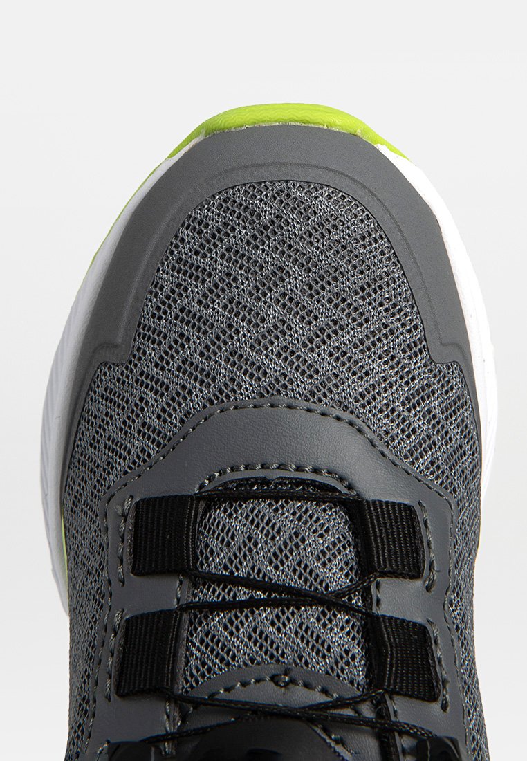 Szare buty sportowe z siateczkową cholewką, czarnymi sznurowadłami i białą podeszwą. Oferują żywy zielony akcent na czubku oraz teksturowane detale.