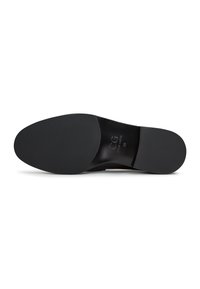 Semelle d'une chaussure habillée en cuir noir montrant une semelle lisse, un talon bas et une taille 39 avec le logo de la marque CG embossé sur la zone de la voûte plantaire.