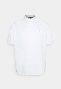 Polo blanc à manches courtes avec col, patte à deux boutons et petit logo rectangulaire sur la poitrine gauche.
