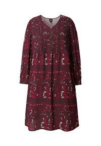 Bordeauxfarbenes Kleid mit langen Ärmeln, V-Ausschnitt und gerafftem Oberteil. Das Kleid hat ein kräftiges Muster in Rot und Weiß, ist knielang und hat eine lockere Passform.