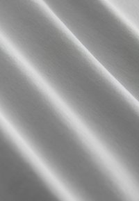 Witte stof met een gladde textuur, voorzien van subtiele diagonale lijnen en plooien die zachte schaduwen en highlights creëren.