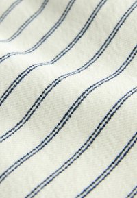Tissu blanc avec de fines double rayures bleu marine uniformément espacées, courant en diagonale sur la surface texturée.