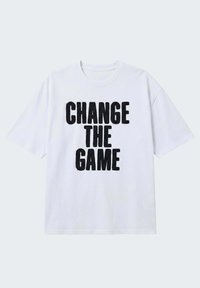 T-shirt blanc à manches courtes avec un texte noir en lettres capitales audacieuses indiquant "CHANGE THE GAME" centré sur le devant.
