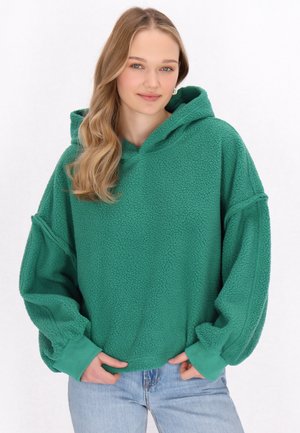 Zöld bolyhos kapucnis pulóver texturált felülettel, oversized fazonnal és kenguruzsebbekkel. Felszerelt húzózsinórral a kapucnin és bordázott mandzsettákkal rendelkezik.