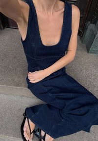 Tume denimist tehtud ülikond, millel on lai kaelus ja laiad sääred, mööda keha liibuv ülemine osa ning esiõmblused. Kombineeritud madala musta sandaaliga.