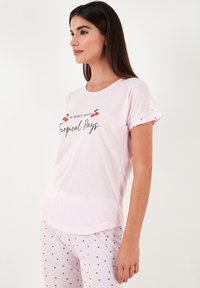 Light pink pajama set featuring a t-shirt with short sleeves and cherry graphics, paired with lightweight pants adorned with a cherry pattern.