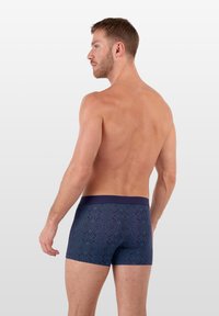 Navy modré trenýrky s geometrickým vzorem, měkká tkanina, elastický pas a délka po stehna, zdůrazňující přiléhavý design.