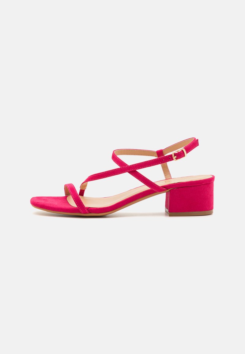 Pink suede heeled sandals with a block heel, crisscross straps, and an adjustable ankle strap. Smooth inner lining and textured outsole.