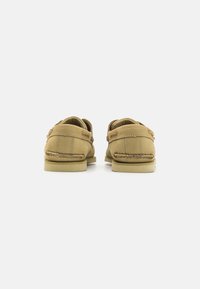 Loafers din piele maro, cu toc mic, textură moale, detalii cusute și hardware minim. Designul dispune de un spate deschis pentru purtare ușoară.