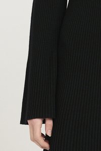 Black ribbed dress featuring long sleeves with flared cuffs, showcasing a textured fabric and a fitted design along the body.
