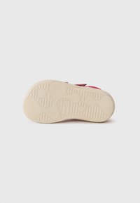 Suola di scarpa rosa chiaro con motivo testurizzato e scanalature per una buona presa; materiale in gomma beige morbida; progettata per comfort e stabilità.