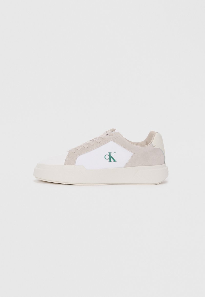Witte en beige sneaker met suede en canvas materialen, gelaagd ontwerp, ronde neus, vetersluiting en groene logo detail.