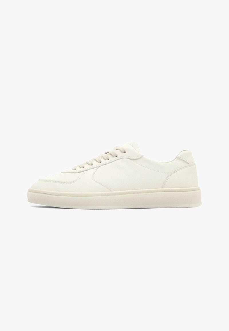 Nízký teniskový model z krémově bílé kůže s předním šněrováním a plochou gumovou podrážkou, zobrazený z boku na bílém pozadí.