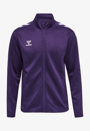 Lilla træningsjakke med høj krave, fuld lynlås foran og hvide chevron-detaljer på skuldrene. Lavet af glat, letvægtsstof.