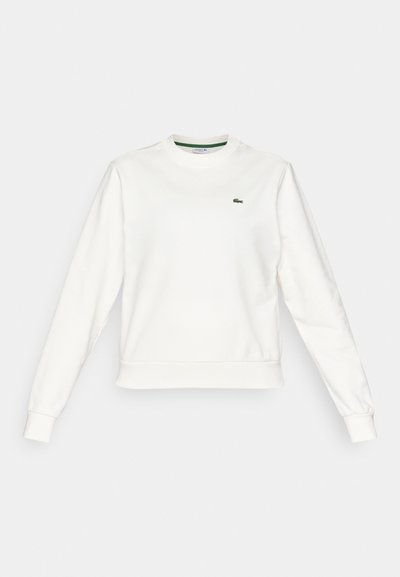 Sweatshirt blanc à col rond avec manches longues, poignets et ourlet côtelés, arborant un petit logo de crocodile vert sur la poitrine gauche.
