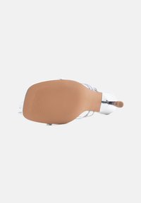 Ασημί σανδάλι με τακούνι και λεπτά λουράκια, τετράγωνη μύτη και ταμπά σόλα με αντιολισθητικό σχέδιο, φωτογραφημένο από κάτω.