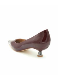 Pantofole in vernice bordeaux con punta affusolata e tacco cono metallico basso, caratterizzate da una finitura lucida e sinuosa e da un cut-out laterale.