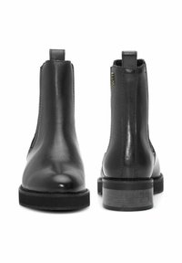 Czarne skórzane botki za kostkę z zaokrąglonymi noskami, elastycznymi panelami bocznymi i tylnymi pętelkami do ściągania. Solidne obcasy z teksturowaną czarno-szarą podeszwą.