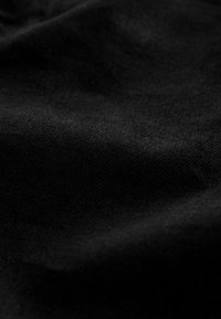 Schwarzer Stoff mit glatter Textur, der feine Webmuster und subtile Lichtreflexionen zeigt.