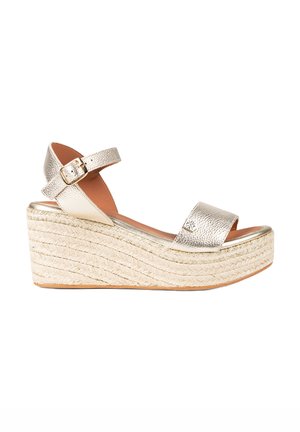 Sandalias de cuña metálicas plateadas con punta abierta, correa en el tobillo y parte superior texturizada. Plataforma estilo alpargata tejida con un acabado natural.