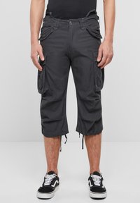 Tummanharmaat cargo-shortsit sivutaskuilla, säädettävillä nyörireunuksilla ja napillisesti suljettavat, yhdistettynä mustavalkoisiin lenkkareihin.