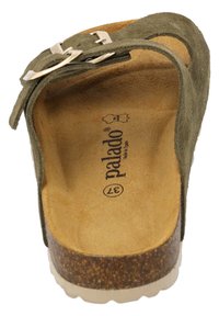 Sandale à glissière en suede vert avec une semelle en liège. Comprend une sangle avec une boucle en métal. L'intérieur est beige avec un marquage en relief.