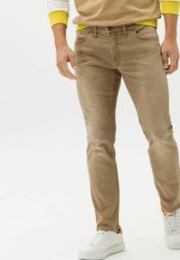 Vaqueros beige slim fit fabricados en denim, con un diseño clásico de cinco bolsillos, detalles de costura sutiles y una textura suave.