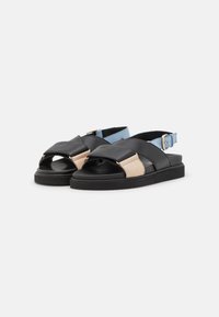 Sandale din piele negre și bej, cu vârf deschis, design cu bretele încrucișate și o curea ajustabilă la gleznă de culoare albastră deschisă. Talpă plată din cauciuc.