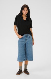 Čierna polokošeľa, deninové culottes, hnedé topánky s robustnou podrážkou a šedé ponožky. Ľahká textúra na košeli, stredné umývanie pre denim.