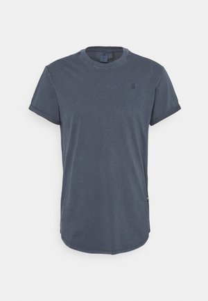 T-shirt manches courtes bleu foncé à col rond avec un petit logo poitrine et un ourlet arrondi sur fond blanc uni.