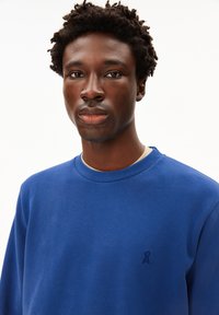 Blauwe sweatshirt van katoen, met een ronde halslijn en lange mouwen. Een klein logo is gedrukt op de linkerkant van de borst.