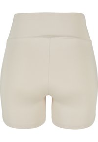 Shorts beige taille haute sans coutures avec un tissu lisse, sans logos ni motifs visibles, vus de dos.