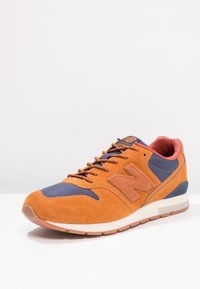 Oranžové semišové tenisky s námořnickou síťovinou, šněrováním vpředu, výrazným světle hnědým logem "N" a bílou mezipodešví, s texturovanou gumovou podešví.