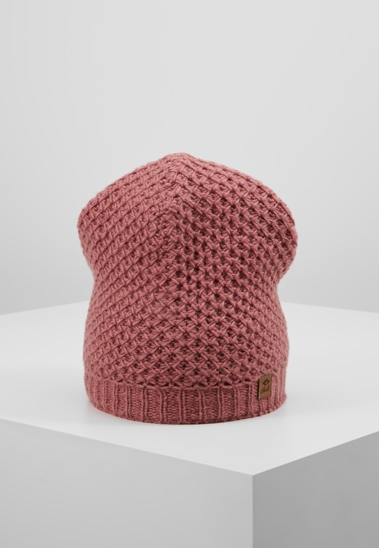 Bonnet tricoté rose avec un motif en losange texturé et une petite étiquette rectangulaire en cuir de la marque sur le bord côtelé, présenté sur une surface blanche.