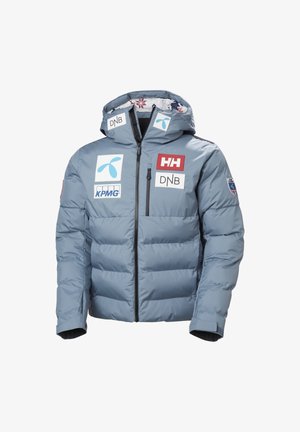 Veste d'hiver matelassée bleu clair avec capuche, fermeture éclair à l'avant, plusieurs logos de sponsors dont Helly Hansen, DNB, KPMG, et badge de l'équipe norvégienne.