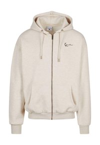 Svetlo béžová mikina na zips vyrobená z mäkkého materiálu, s kapucňou, dvoma prednými vreckami, pružnými manžetami a vyšívaným logom na hrudi.