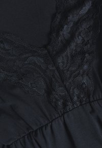 Vestuário preto com detalhes em renda na gola, apresentando uma textura de tecido suave e uma cintura franzida para uma silhueta ajustada.