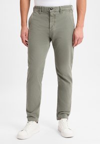 Olijfgroene chino's met een rechte snit, vijf zakken en een knoopsluiting, gecombineerd met witte sneakers. Glad stof, lichtgewicht ontwerp.