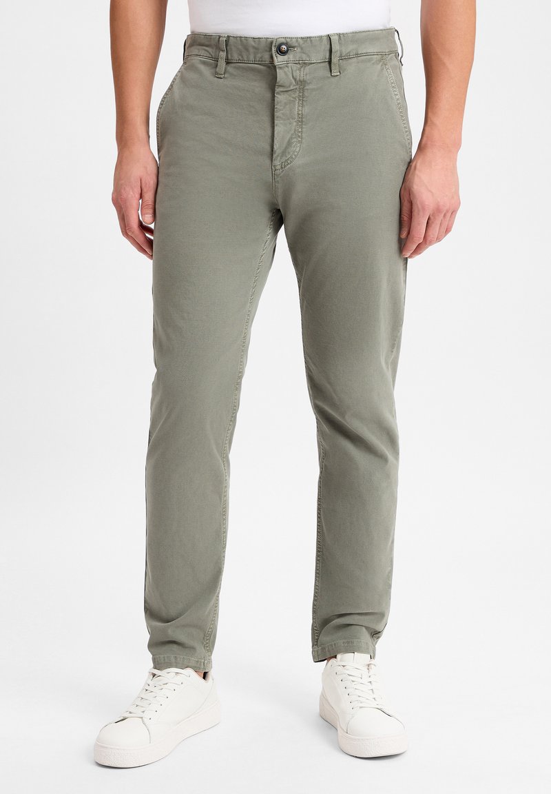 Olijfgroene chino's met een rechte snit, vijf zakken en een knoopsluiting, gecombineerd met witte sneakers. Glad stof, lichtgewicht ontwerp.