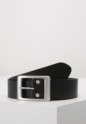 Czarny skórzany pasek zwinięty na białej powierzchni, z kwadratową srebrną klamrą i dwoma metalowymi nitami blisko szpilki.