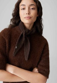 Maglione marrone a maglia sfocata con maniche corte, caratterizzato da un collo con sciarpa annodata, texture morbida e un dettaglio logo sottile.